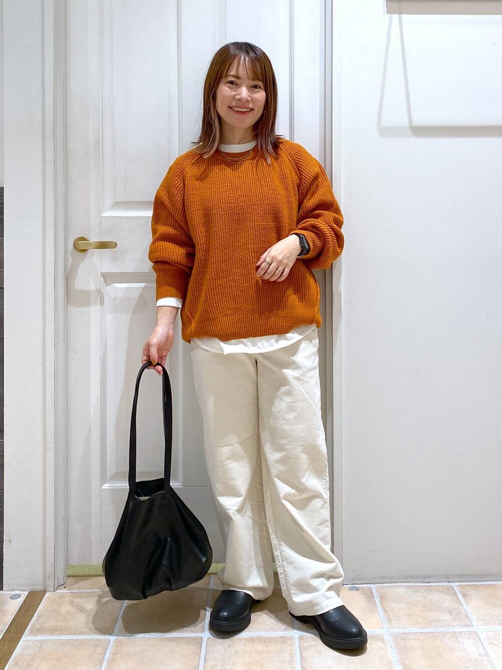 ベージュ系のその他パンツ、ブラック系のブーツ、オレンジ系のニット/セーターを着用したレディースの秋コーディネートの3枚目の写真