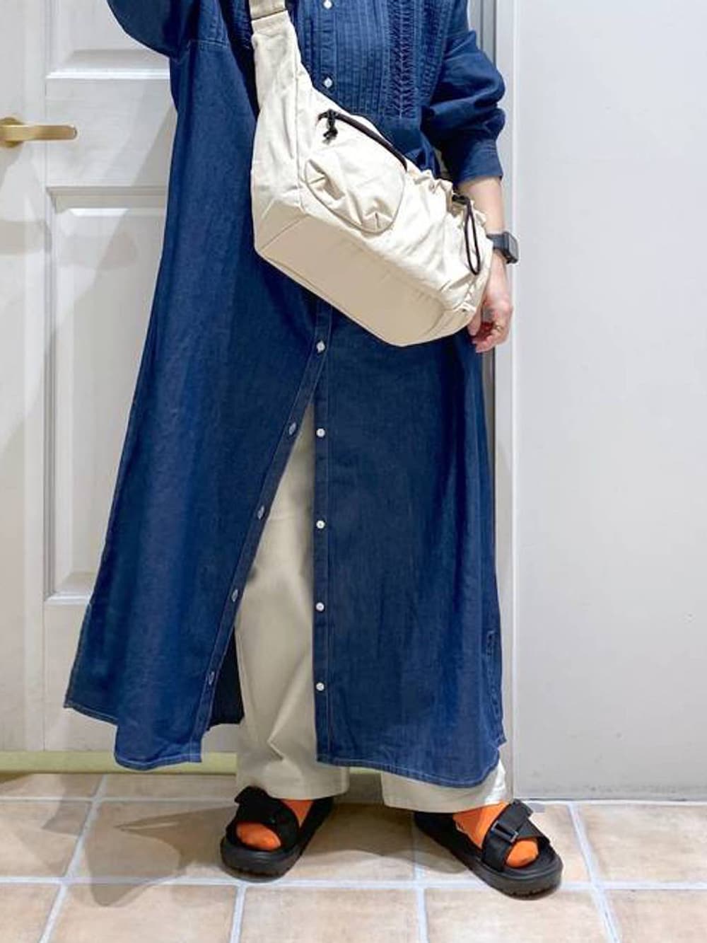 ブラック系のサンダル、ホワイト系のショルダーバッグ、ブルー系のワンピースを着用したレディースの春コーディネートの4枚目の写真