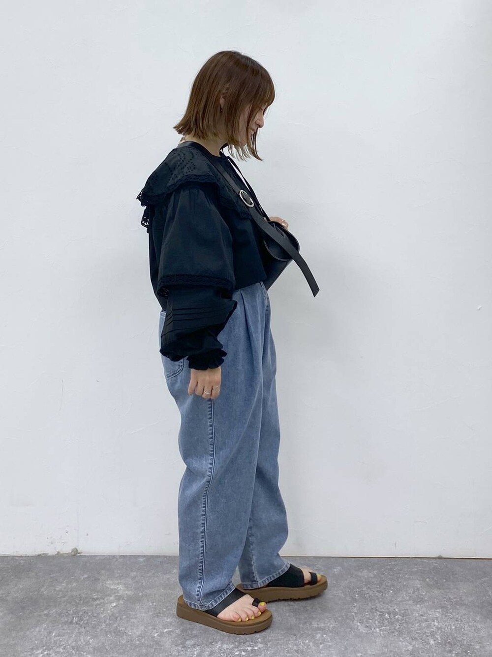 ブラック系のサンダル、ブルー系のデニムパンツ、ブラック系のショルダーバッグを着用したレディースの夏コーディネートの3枚目の写真
