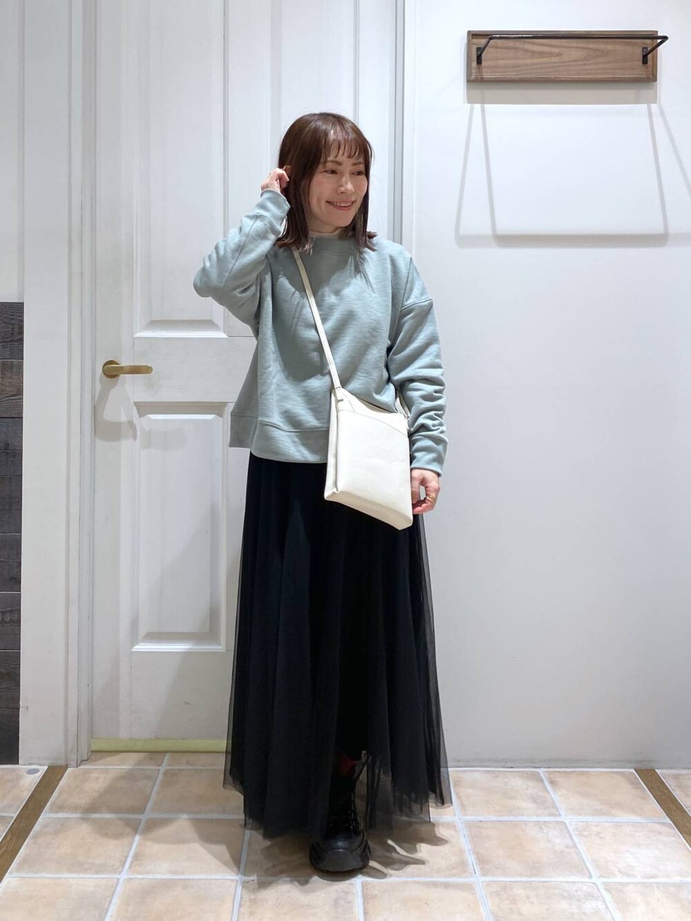 グリーン系のスウェット、ホワイト系のTシャツ/カットソー、ブラック系のスニーカーを着用したレディースの冬コーディネートの2枚目の写真