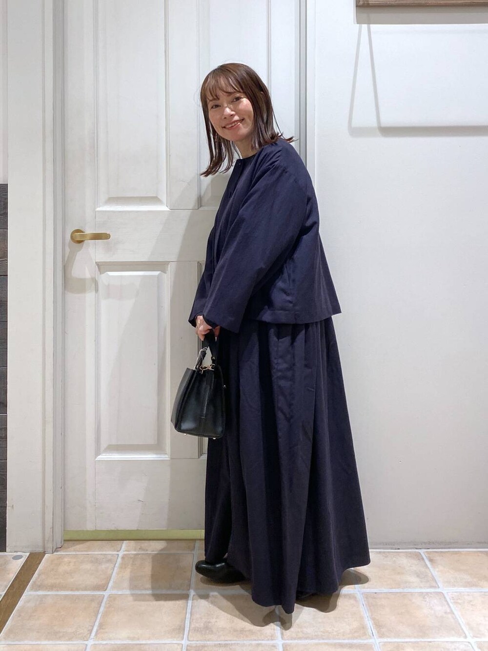 ブラック系のパンプス、ブルー系のセットアップ、その他のピアス（両耳用）を着用したレディースの冬コーディネートの5枚目の写真