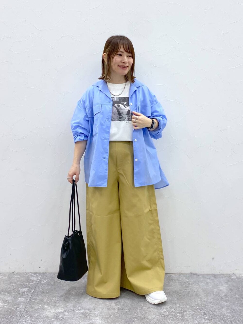 ホワイト系のスニーカー、ベージュ系のチノパンツ、ブラック系のトートバッグを着用したレディースの春コーディネートの3枚目の写真