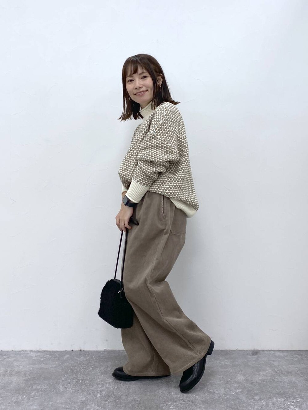グレー系のその他パンツ、ブラック系のブーツ、ホワイト系のニット/セーターを着用したレディースの秋コーディネートの5枚目の写真