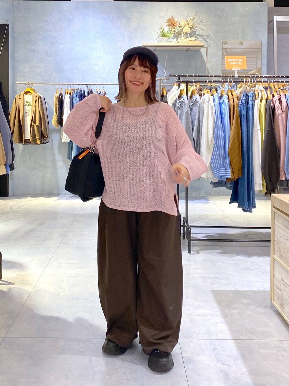 ピンク系のニット/セーター、ブラック系のショルダーバッグ、ブラック系のスニーカーを着用したレディースの秋コーディネートの3枚目の写真