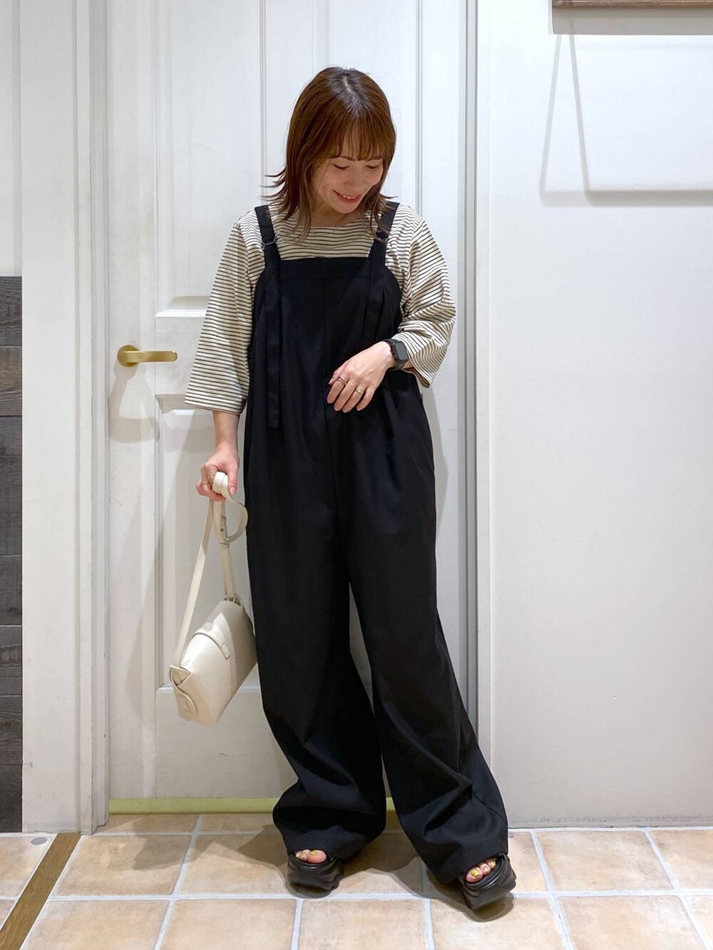 ブラック系のサンダル、ホワイト系のショルダーバッグ、シルバー系のネックレスを着用したレディースの夏コーディネートの3枚目の写真