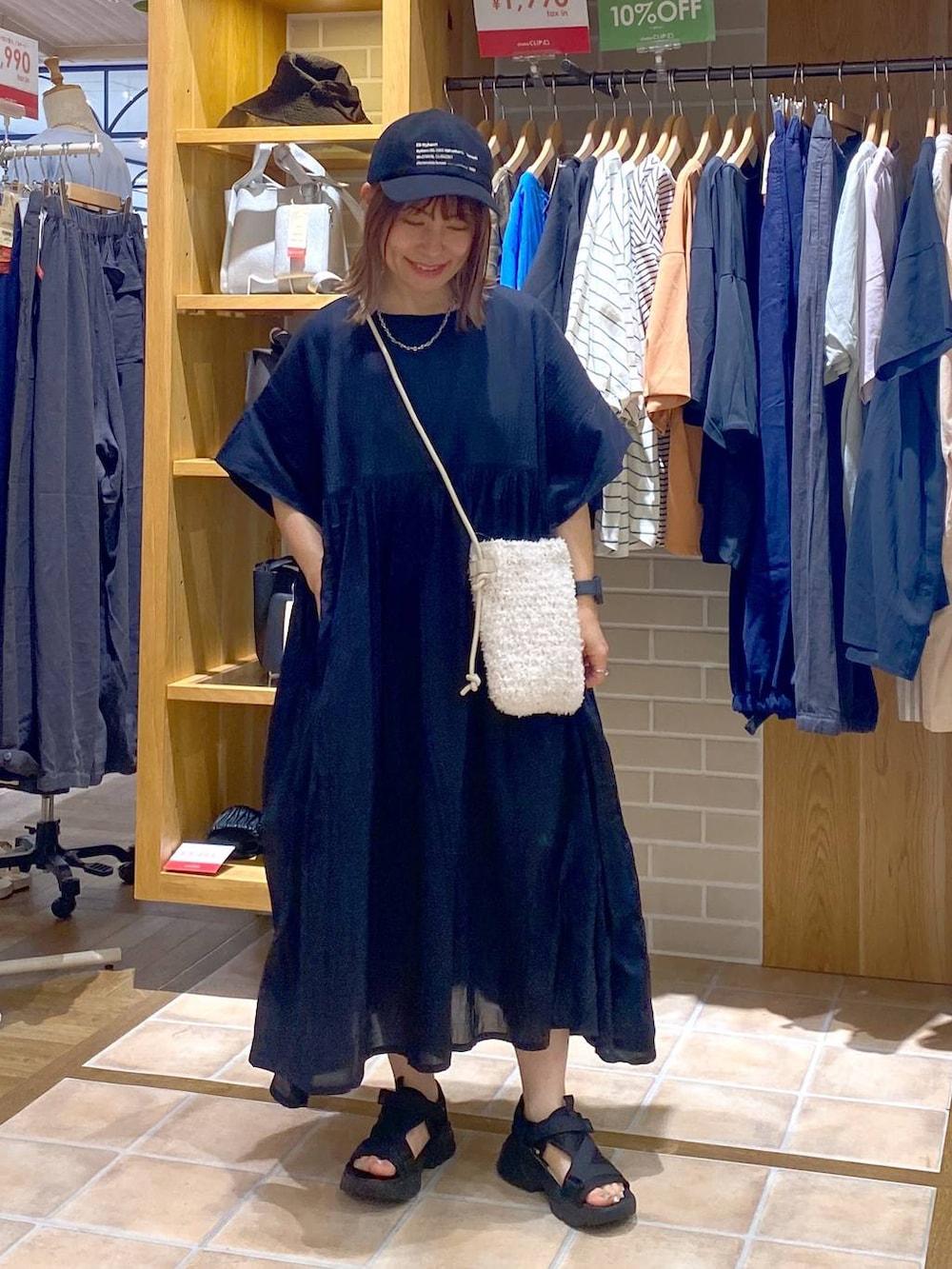 ホワイト系のショルダーバッグ、ブラック系のワンピース、ブラック系のサンダルを着用したレディースの夏コーディネートの3枚目の写真