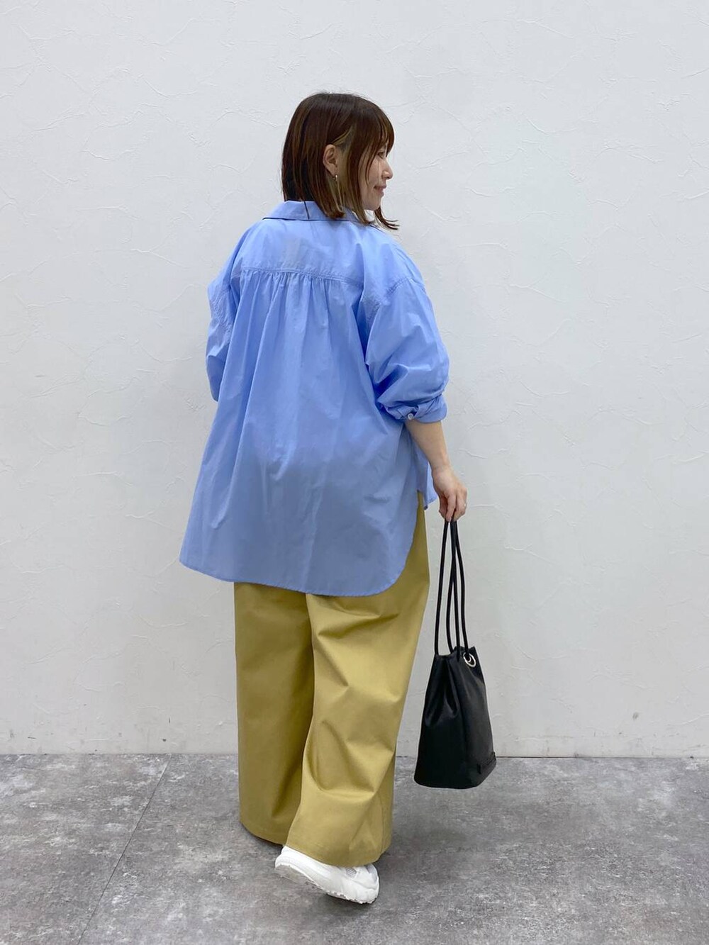 ホワイト系のスニーカー、ベージュ系のチノパンツ、ブラック系のトートバッグを着用したレディースの春コーディネートの5枚目の写真