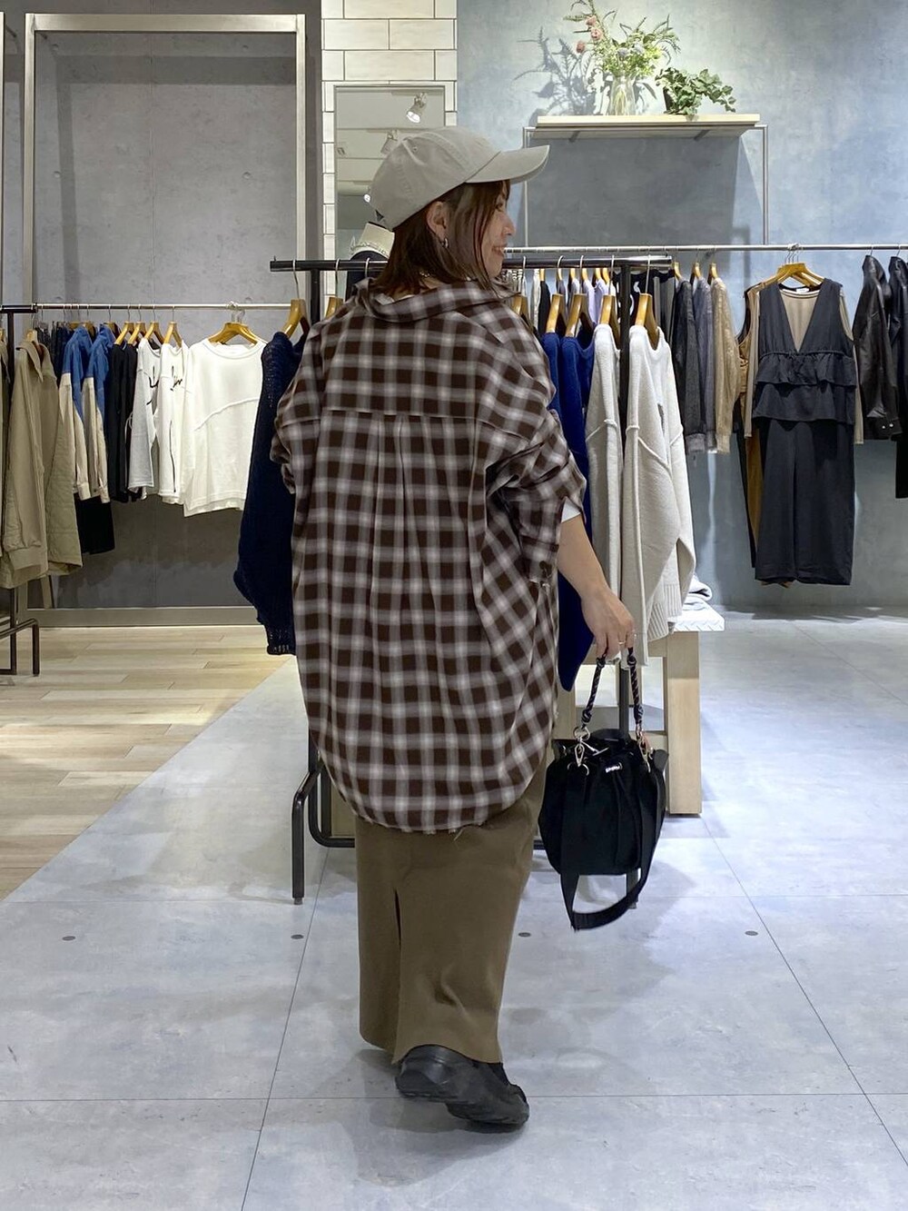 ブラック系のショルダーバッグ、ブラウン系のスカート、ブラック系のスニーカーを着用したレディースの秋コーディネートの5枚目の写真