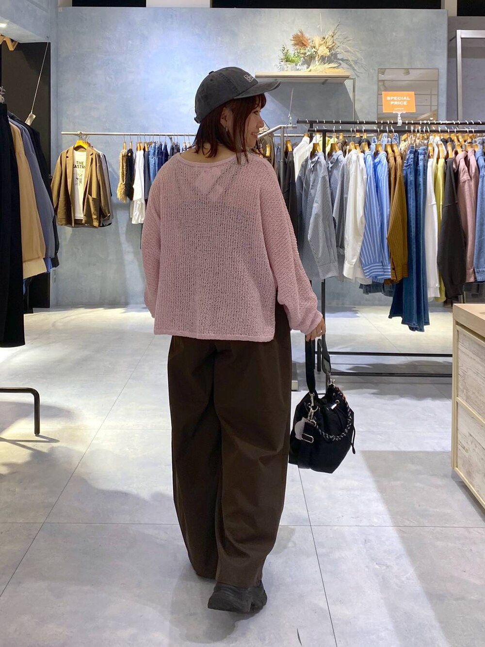 ピンク系のニット/セーター、ブラック系のショルダーバッグ、ブラック系のスニーカーを着用したレディースの秋コーディネートの5枚目の写真