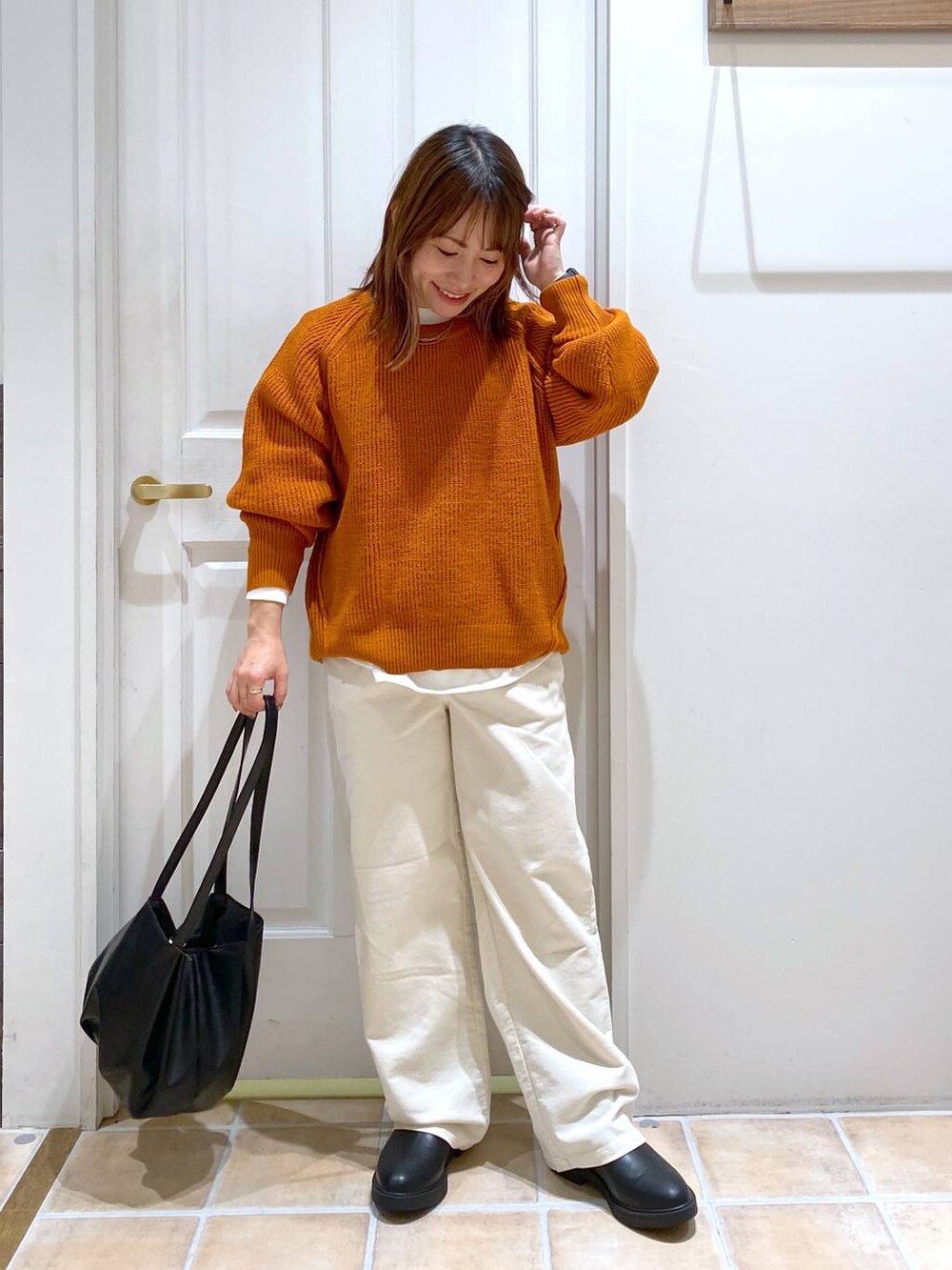 ベージュ系のその他パンツ、ブラック系のブーツ、オレンジ系のニット/セーターを着用したレディースの秋コーディネートの2枚目の写真