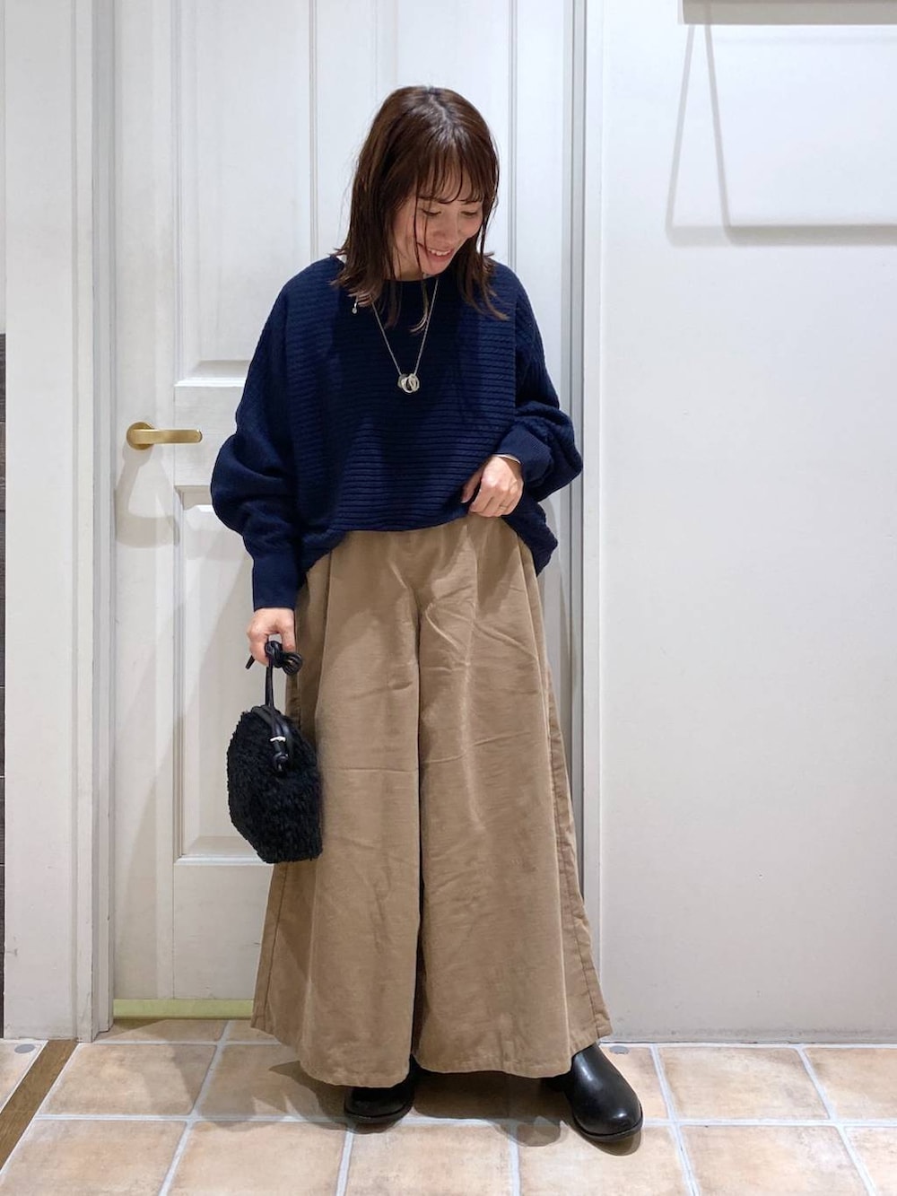 ベージュ系のその他パンツ、ブラック系のブーツ、ブルー系のニット/セーターを着用したレディースの秋コーディネートの2枚目の写真