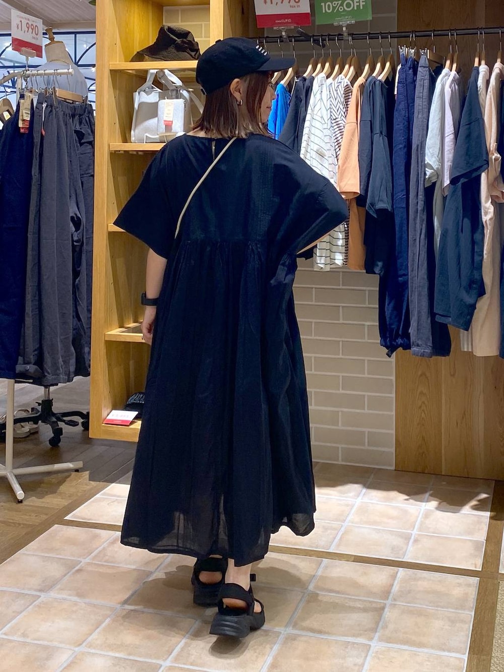 ホワイト系のショルダーバッグ、ブラック系のワンピース、ブラック系のサンダルを着用したレディースの夏コーディネートの5枚目の写真