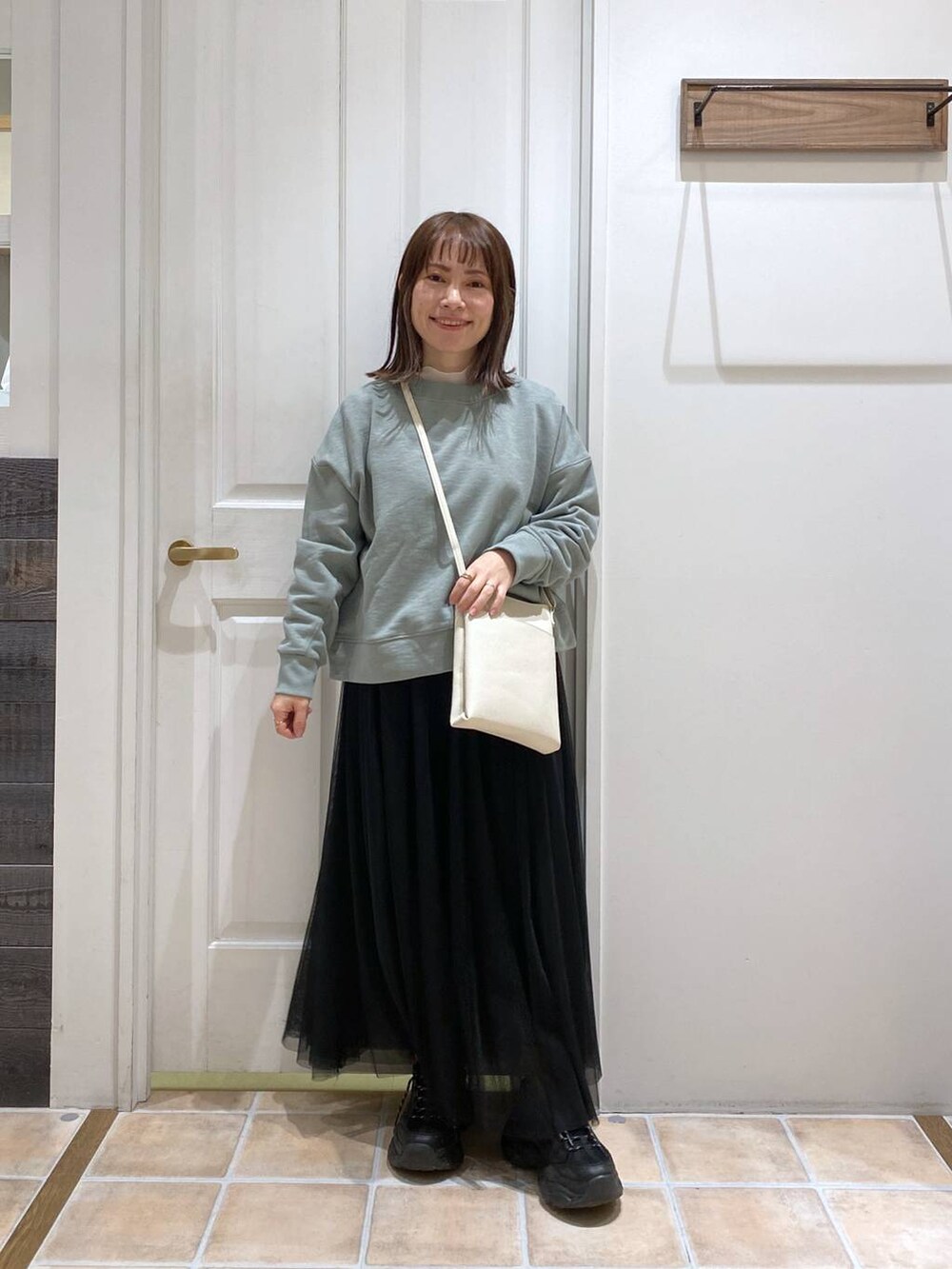 グリーン系のスウェット、ホワイト系のTシャツ/カットソー、ブラック系のスニーカーを着用したレディースの冬コーディネートの3枚目の写真