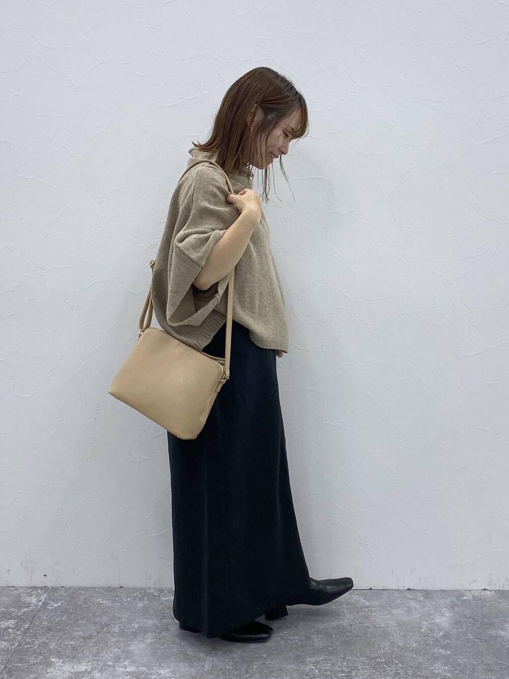 ブラック系のスカート、ベージュ系のベスト、ブラック系のブーツを着用したレディースの秋コーディネートの6枚目の写真