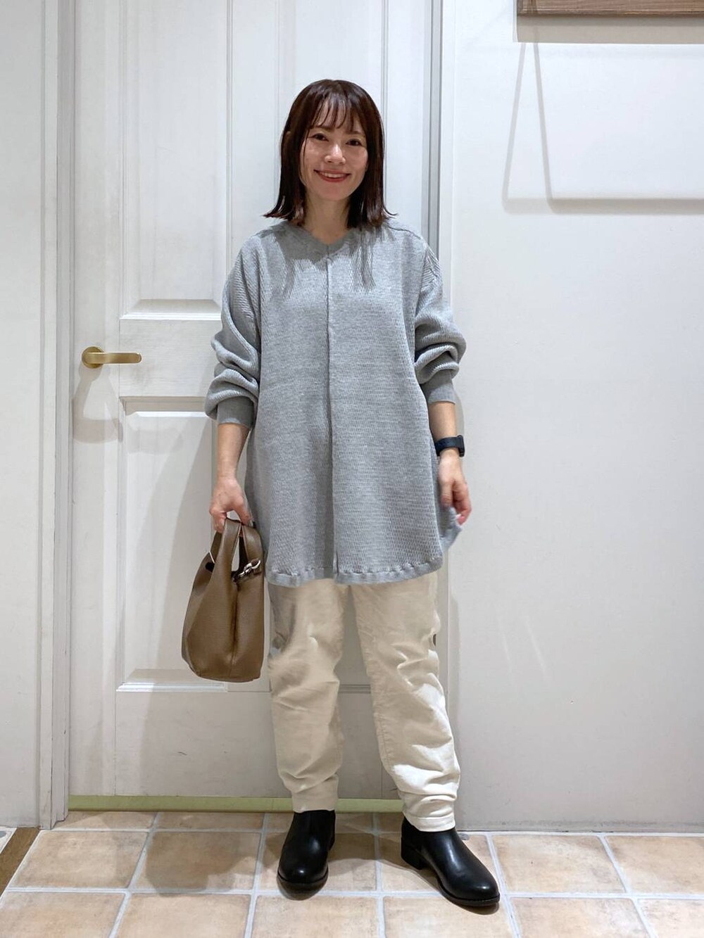 ホワイト系のその他パンツ、ブラック系のブーツ、ブラウン系のショルダーバッグを着用したレディースの秋コーディネートの2枚目の写真