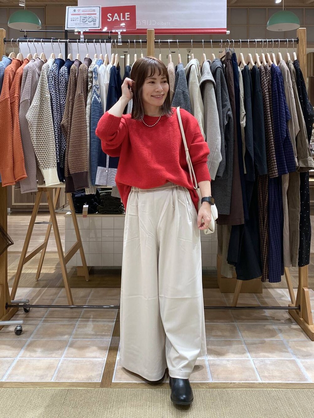 ブラック系のブーツ、ベージュ系のその他パンツ、レッド系のカーディガン/ボレロを着用したレディースの冬コーディネートの3枚目の写真