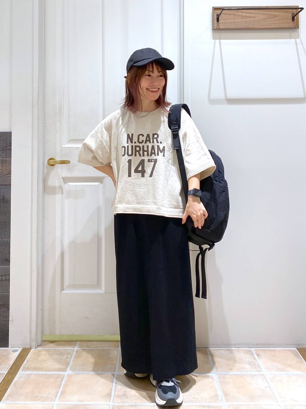 ブラック系のスカート、ブラック系のスニーカー、ベージュ系のTシャツ/カットソーを着用したレディースの秋コーディネートの3枚目の写真
