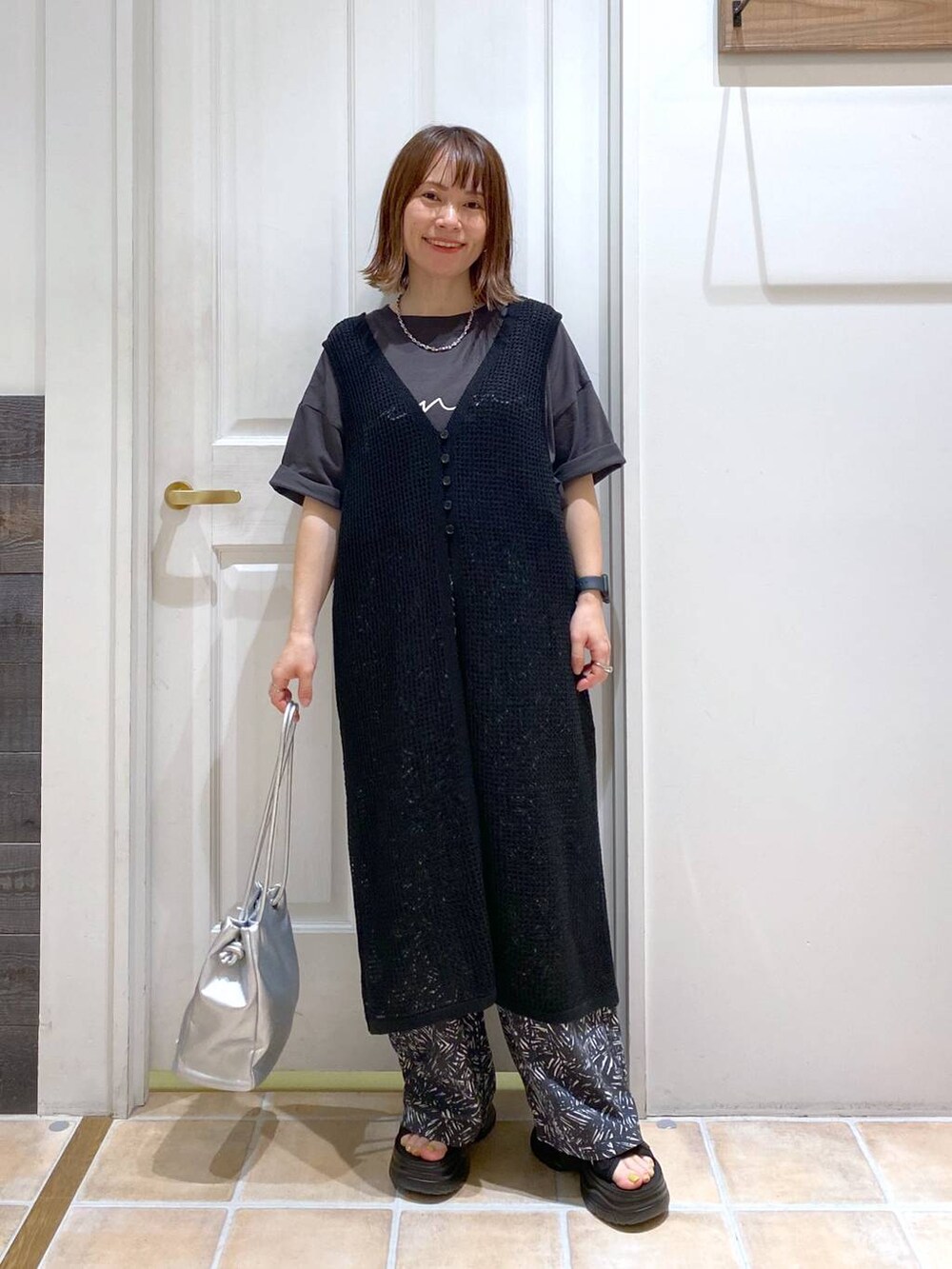 ブラック系のサンダル、ホワイト系のタンクトップ、その他のトートバッグを着用したレディースの夏コーディネートの2枚目の写真