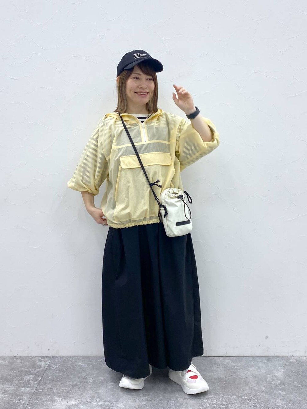 ホワイト系のスニーカー、ブラック系のキャップ、ホワイト系の財布を着用したレディースの春コーディネートの3枚目の写真