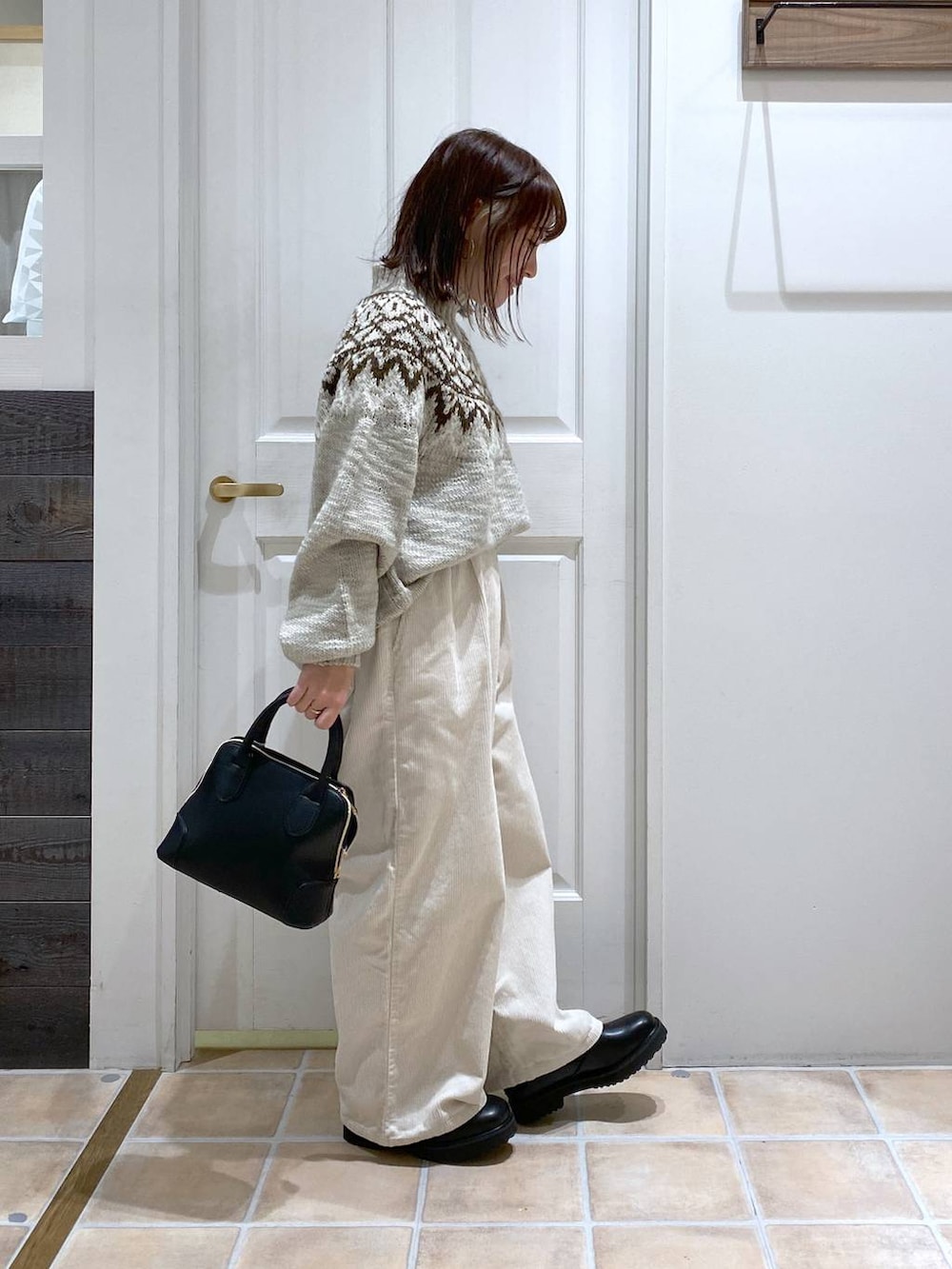 ホワイト系のその他パンツ、ブラック系のブーツ、ブラック系のショルダーバッグを着用したレディースの秋コーディネートの5枚目の写真