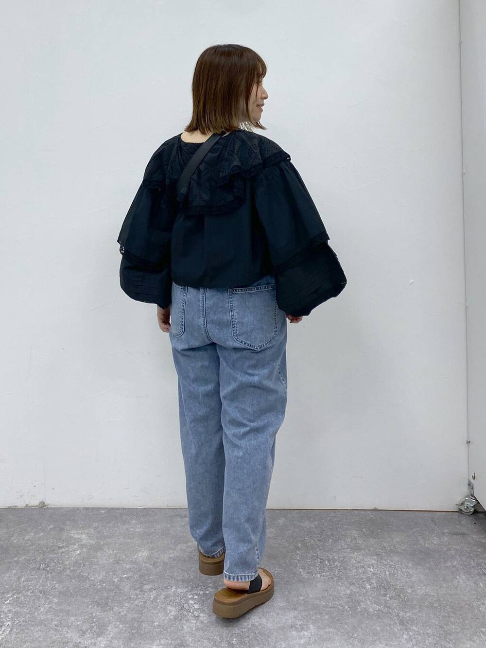 ブラック系のサンダル、ブルー系のデニムパンツ、ブラック系のショルダーバッグを着用したレディースの夏コーディネートの4枚目の写真