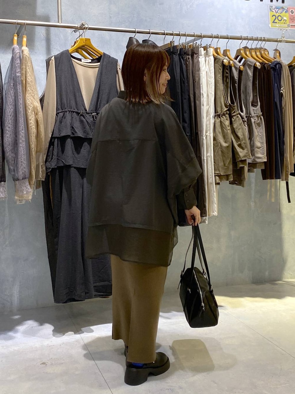 グレー系のシャツ/ブラウス、ブラック系のスカート、ブラック系のサンダルを着用したレディースの秋コーディネートの5枚目の写真