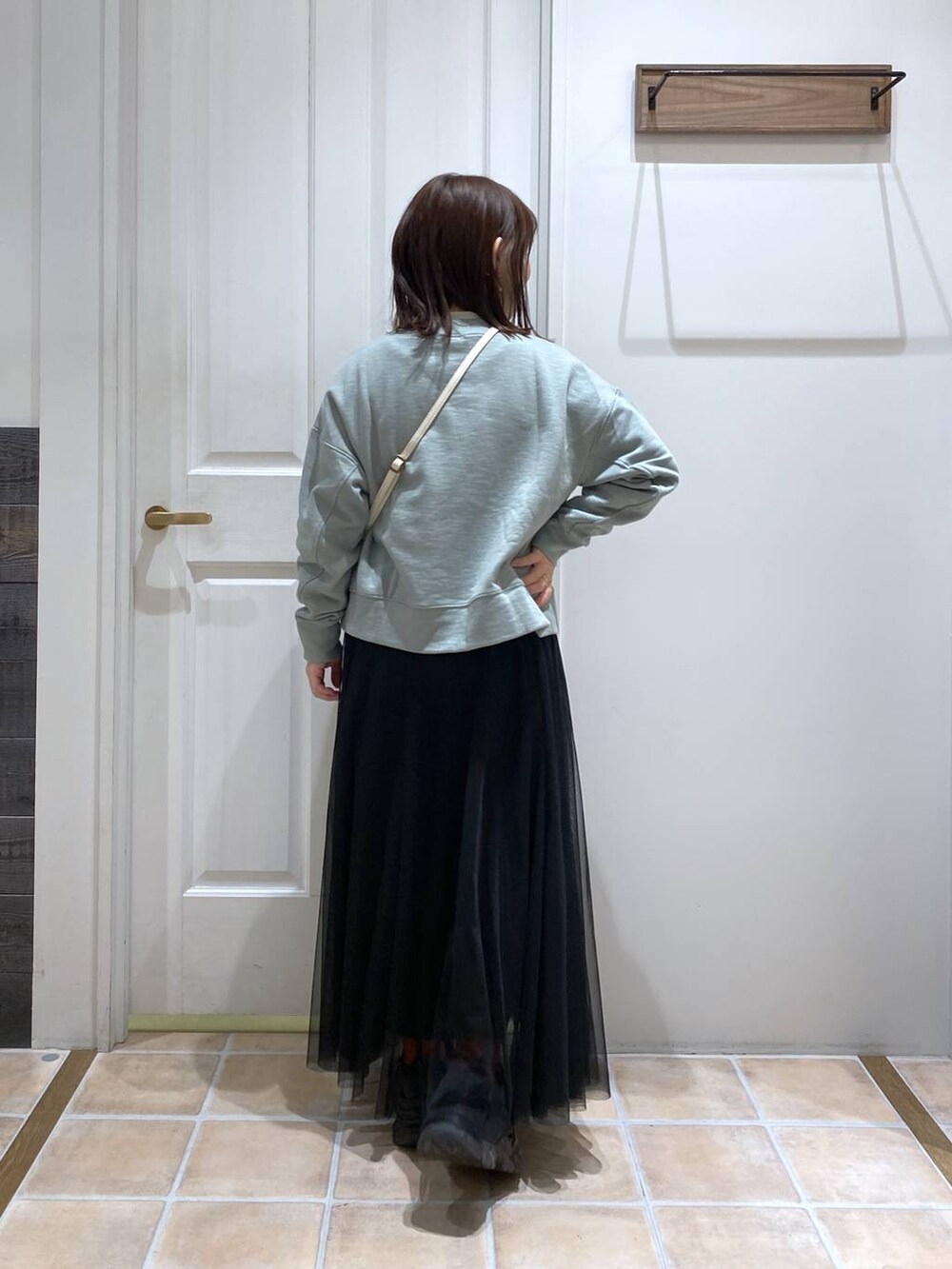 グリーン系のスウェット、ホワイト系のTシャツ/カットソー、ブラック系のスニーカーを着用したレディースの冬コーディネートの6枚目の写真