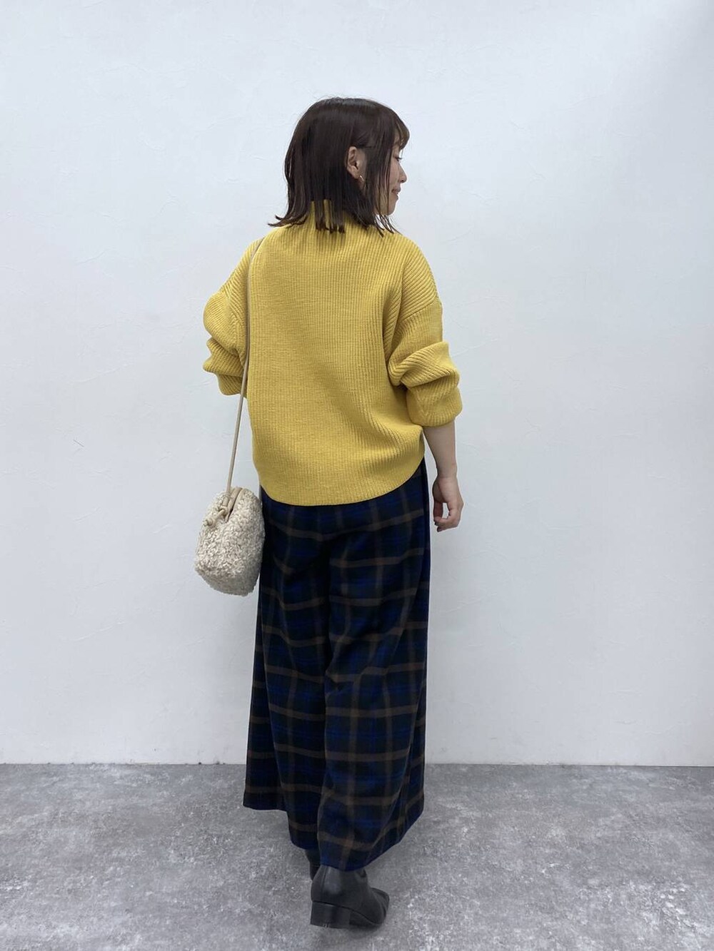 ブラック系のブーツ、イエロー系のニット/セーター、ベージュ系のトートバッグを着用したレディースの秋コーディネートの6枚目の写真