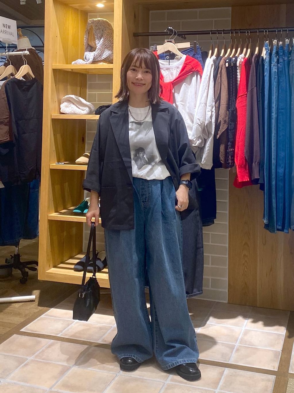 ブルー系のデニムパンツ、ブラック系のローファー、ブラック系のショルダーバッグを着用したレディースの秋コーディネートの3枚目の写真