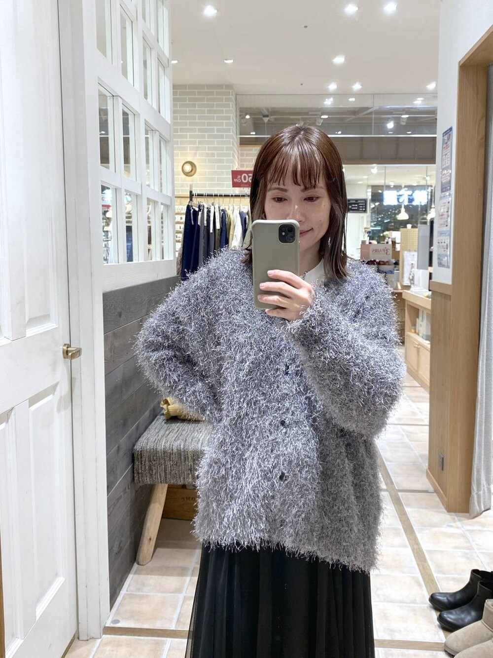 ブラック系のスニーカー、ブラック系のスカート、グレー系のカーディガン/ボレロを着用したレディースの冬コーディネートの5枚目の写真