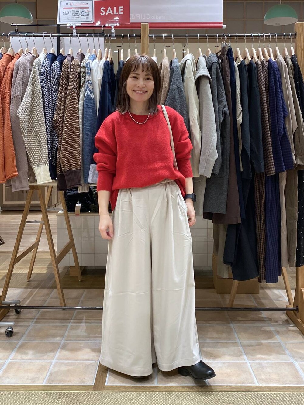 ブラック系のブーツ、ベージュ系のその他パンツ、レッド系のカーディガン/ボレロを着用したレディースの冬コーディネートの2枚目の写真