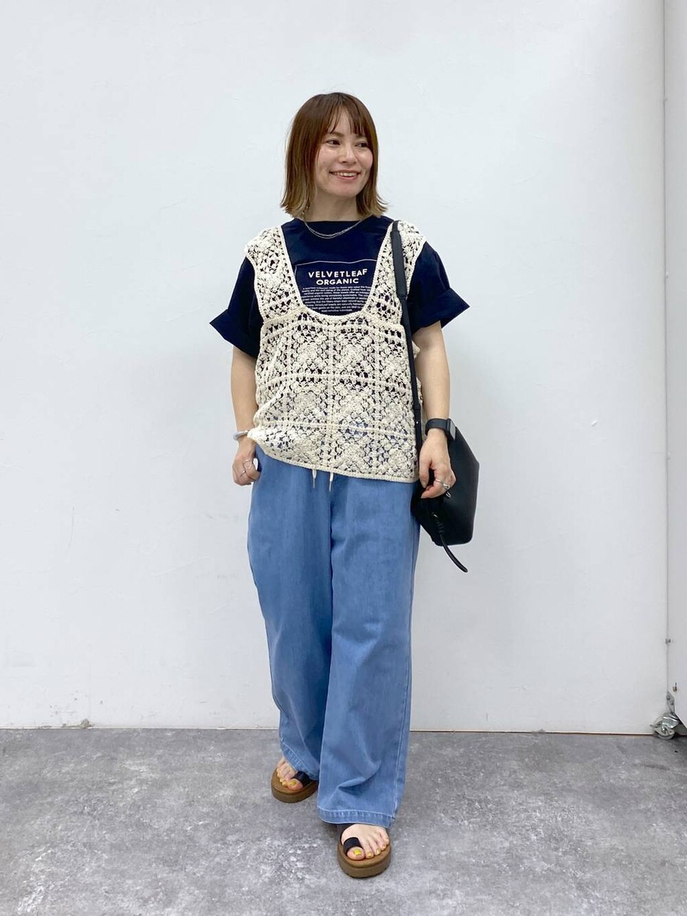 ブラック系のサンダル、ブルー系のデニムパンツ、ブラック系のショルダーバッグを着用したレディースの春コーディネートの3枚目の写真