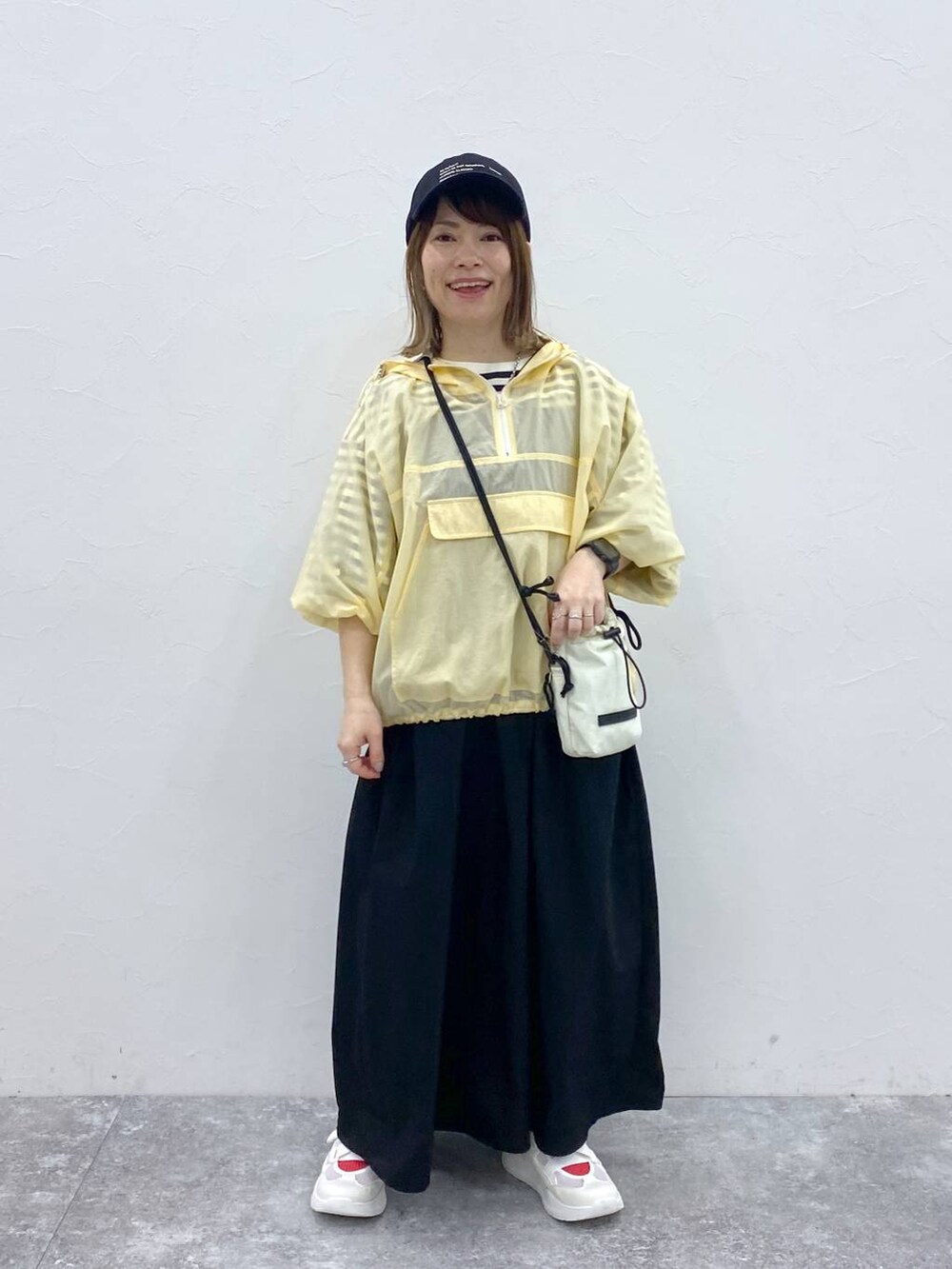 ホワイト系のスニーカー、ブラック系のキャップ、ホワイト系の財布を着用したレディースの春コーディネートの2枚目の写真