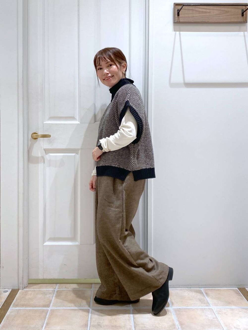 ホワイト系のTシャツ/カットソー、ブラック系のブーツ、ブラック系のベストを着用したレディースの秋コーディネートの3枚目の写真