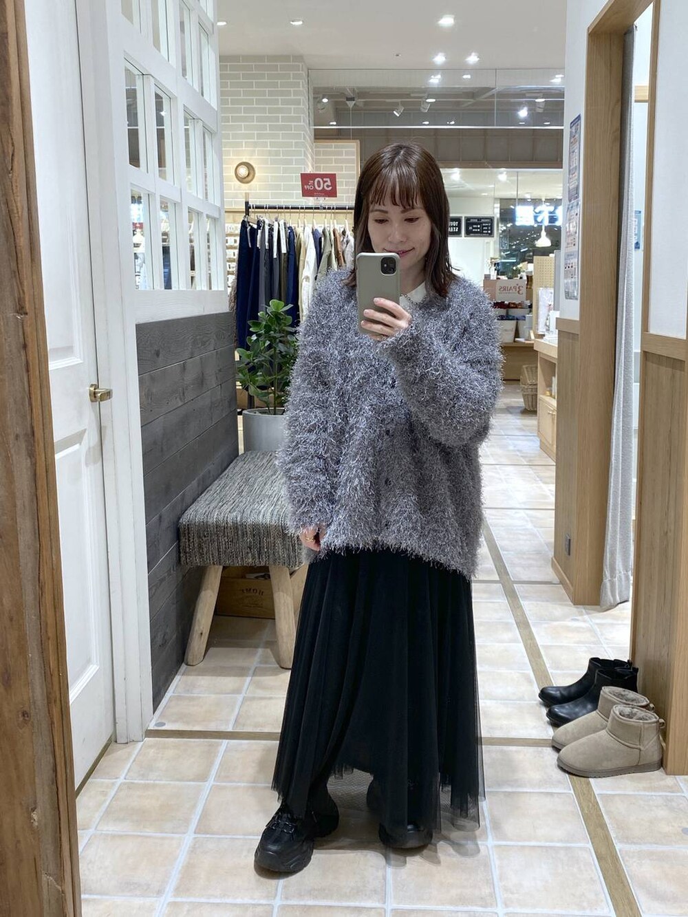 ブラック系のスニーカー、ブラック系のスカート、グレー系のカーディガン/ボレロを着用したレディースの冬コーディネートの4枚目の写真