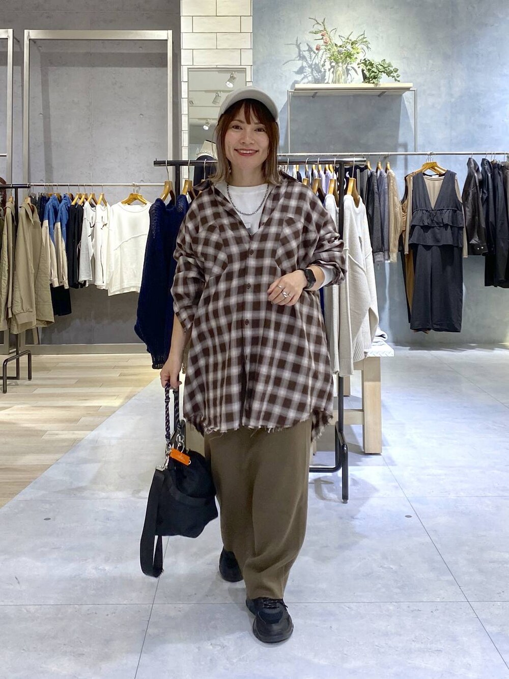 ブラック系のショルダーバッグ、ブラウン系のスカート、ブラック系のスニーカーを着用したレディースの秋コーディネートの3枚目の写真