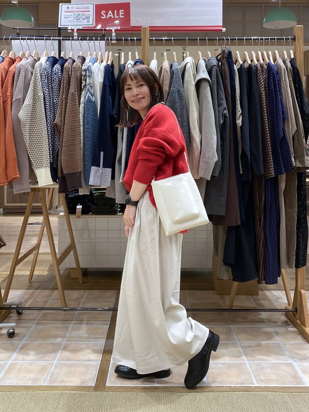 ブラック系のブーツ、ベージュ系のその他パンツ、レッド系のカーディガン/ボレロを着用したレディースの冬コーディネートの6枚目の写真