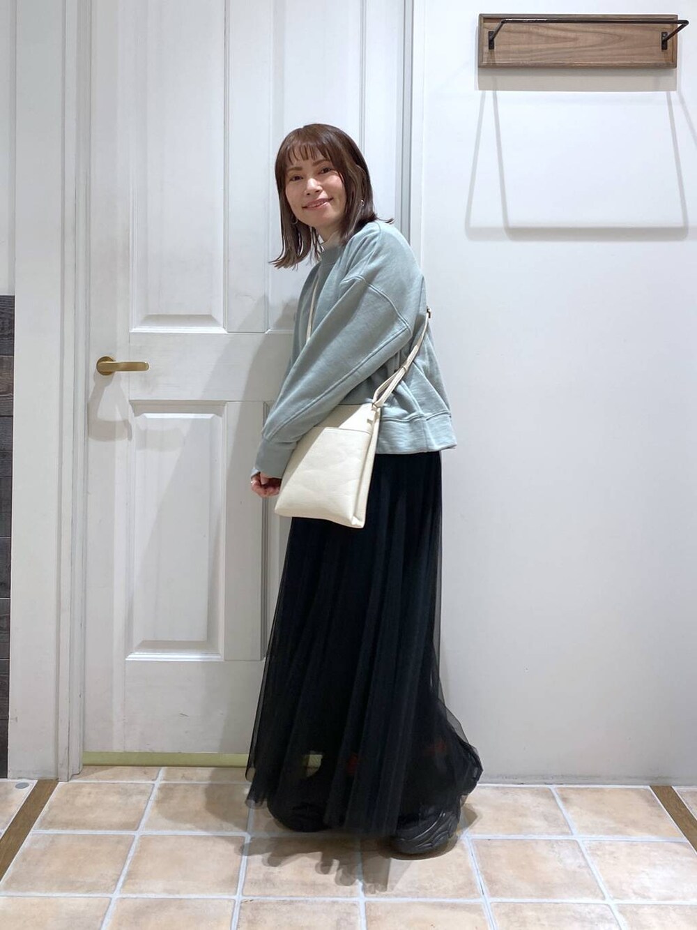 グリーン系のスウェット、ホワイト系のTシャツ/カットソー、ブラック系のスニーカーを着用したレディースの冬コーディネートの4枚目の写真