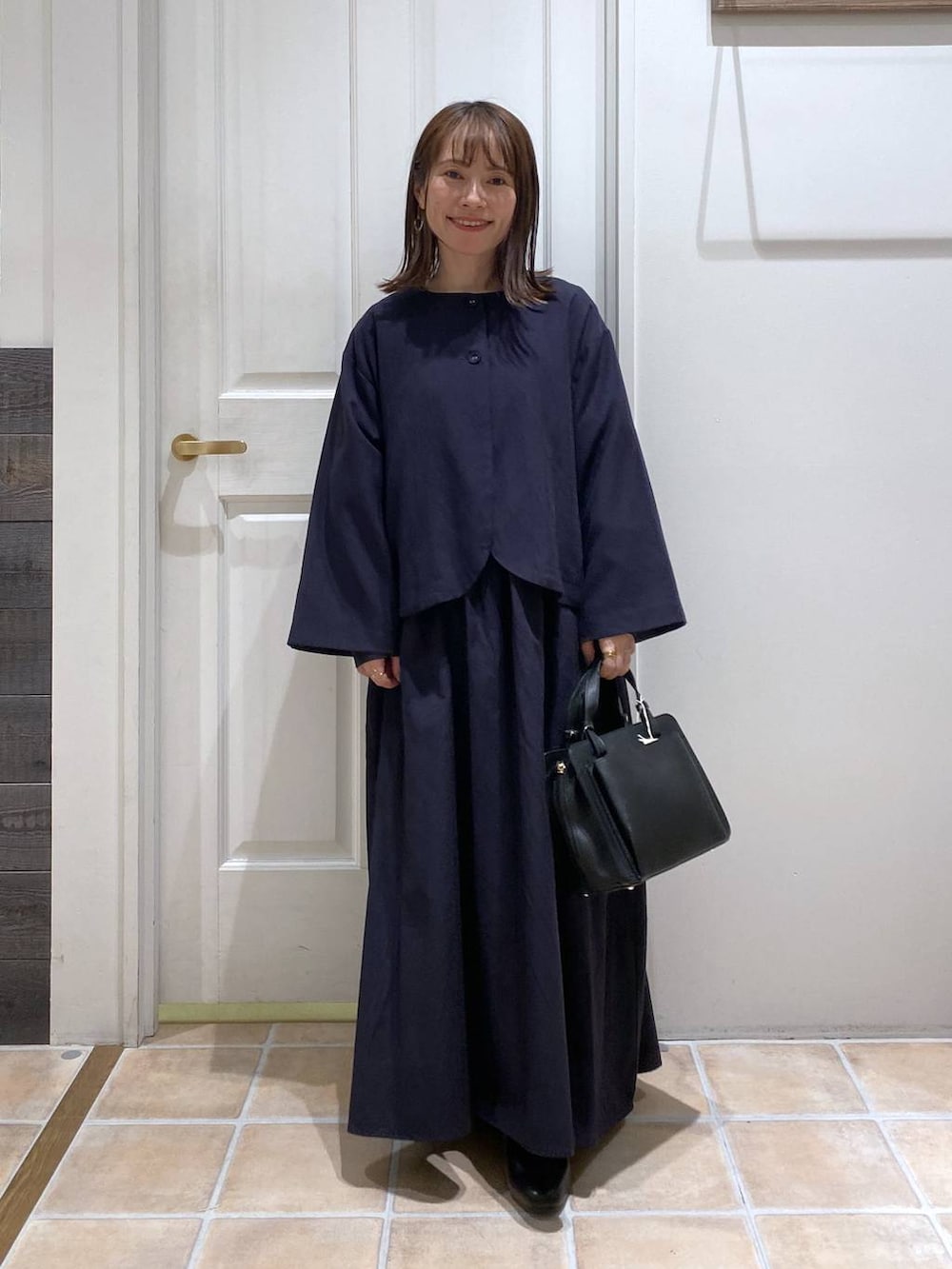 ブラック系のパンプス、ブルー系のセットアップ、その他のピアス（両耳用）を着用したレディースの冬コーディネートの3枚目の写真