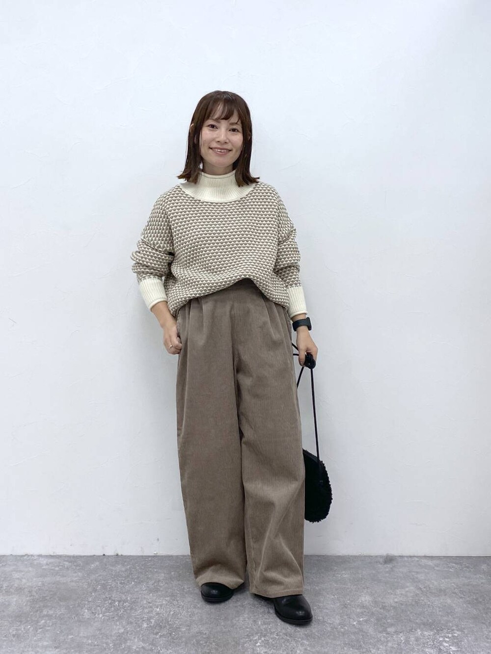 グレー系のその他パンツ、ブラック系のブーツ、ホワイト系のニット/セーターを着用したレディースの秋コーディネートの4枚目の写真