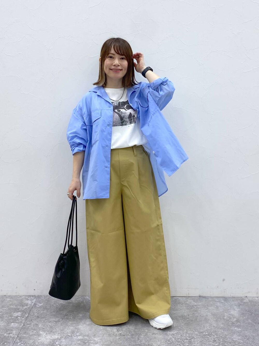 ホワイト系のスニーカー、ベージュ系のチノパンツ、ブラック系のトートバッグを着用したレディースの春コーディネートの2枚目の写真