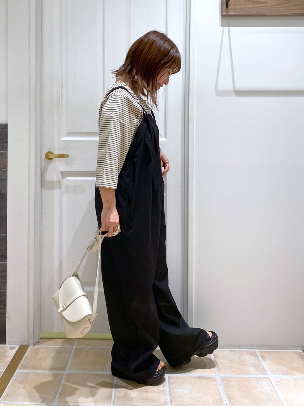 ブラック系のサンダル、ホワイト系のショルダーバッグ、シルバー系のネックレスを着用したレディースの夏コーディネートの5枚目の写真