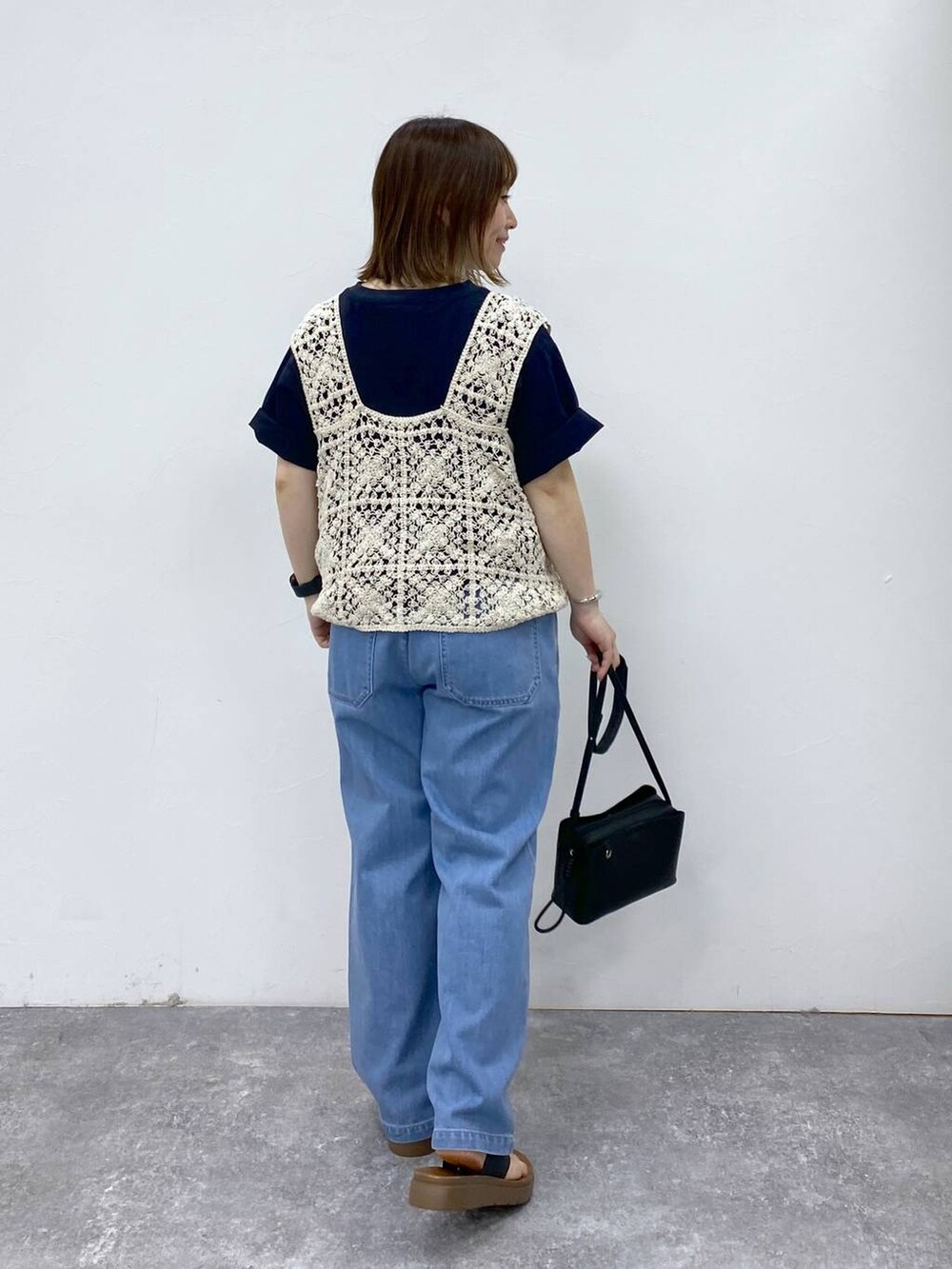 ブラック系のサンダル、ブルー系のデニムパンツ、ブラック系のショルダーバッグを着用したレディースの春コーディネートの5枚目の写真