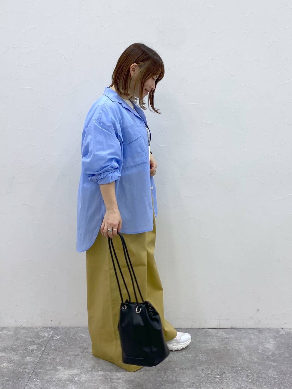 ホワイト系のスニーカー、ベージュ系のチノパンツ、ブラック系のトートバッグを着用したレディースの春コーディネートの4枚目の写真