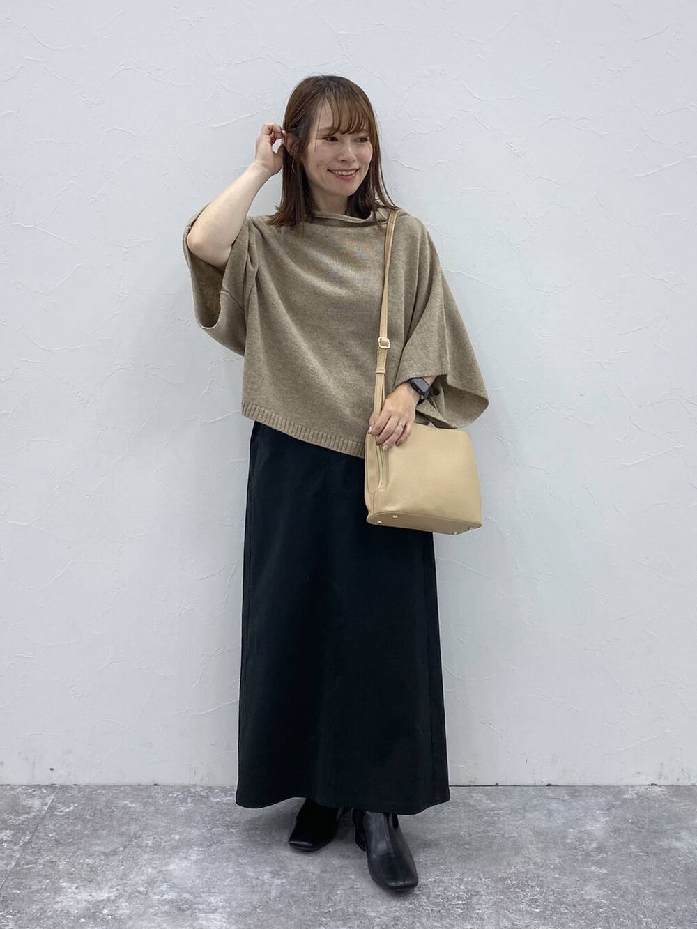 ブラック系のスカート、ベージュ系のベスト、ブラック系のブーツを着用したレディースの秋コーディネートの2枚目の写真