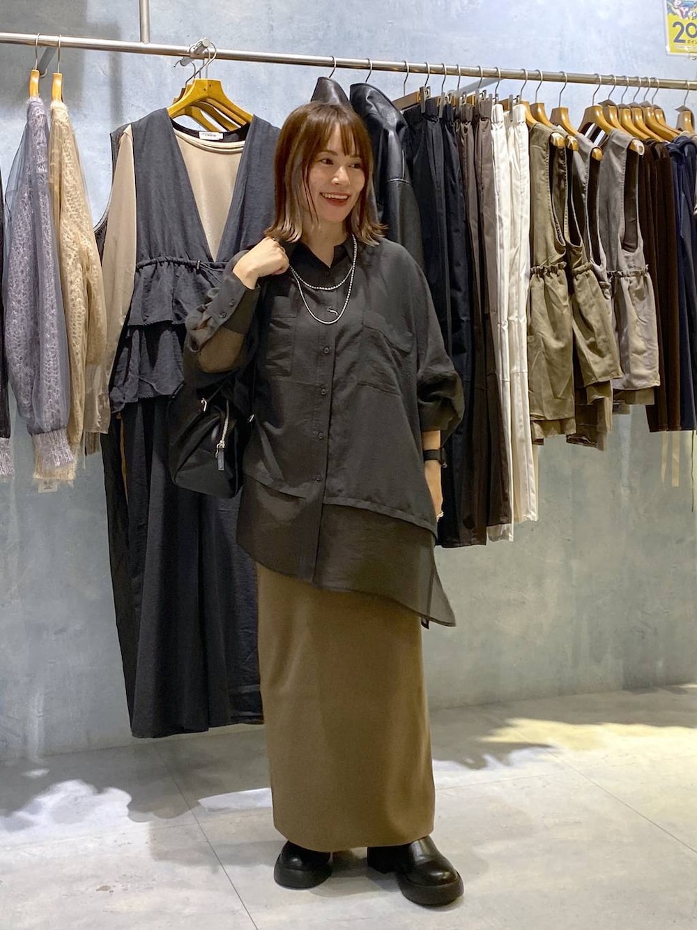 グレー系のシャツ/ブラウス、ブラック系のスカート、ブラック系のサンダルを着用したレディースの秋コーディネートの2枚目の写真