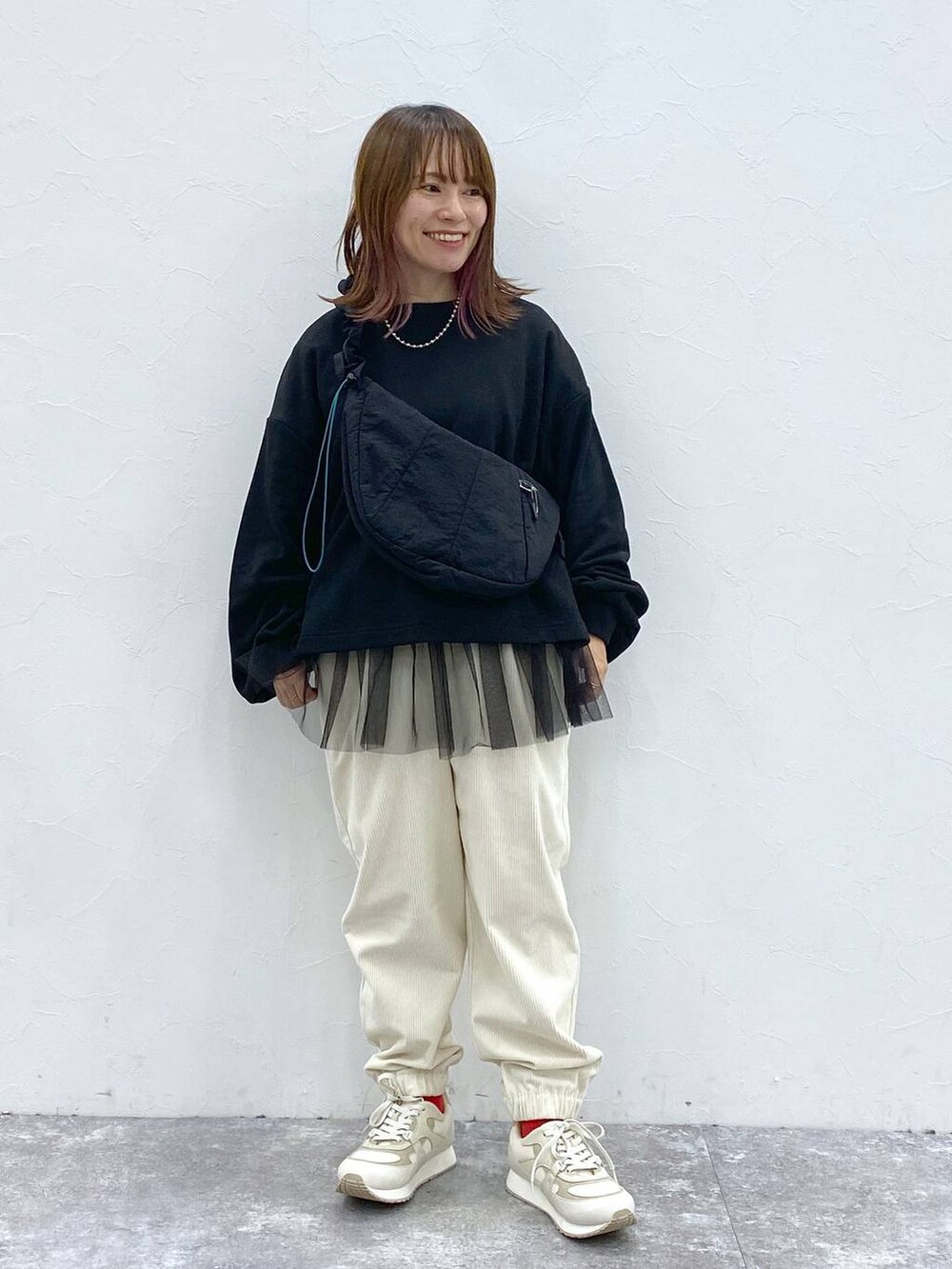 ホワイト系のスニーカー、ブラック系のショルダーバッグ、ブラック系のTシャツ/カットソーを着用したレディースの秋コーディネートの3枚目の写真