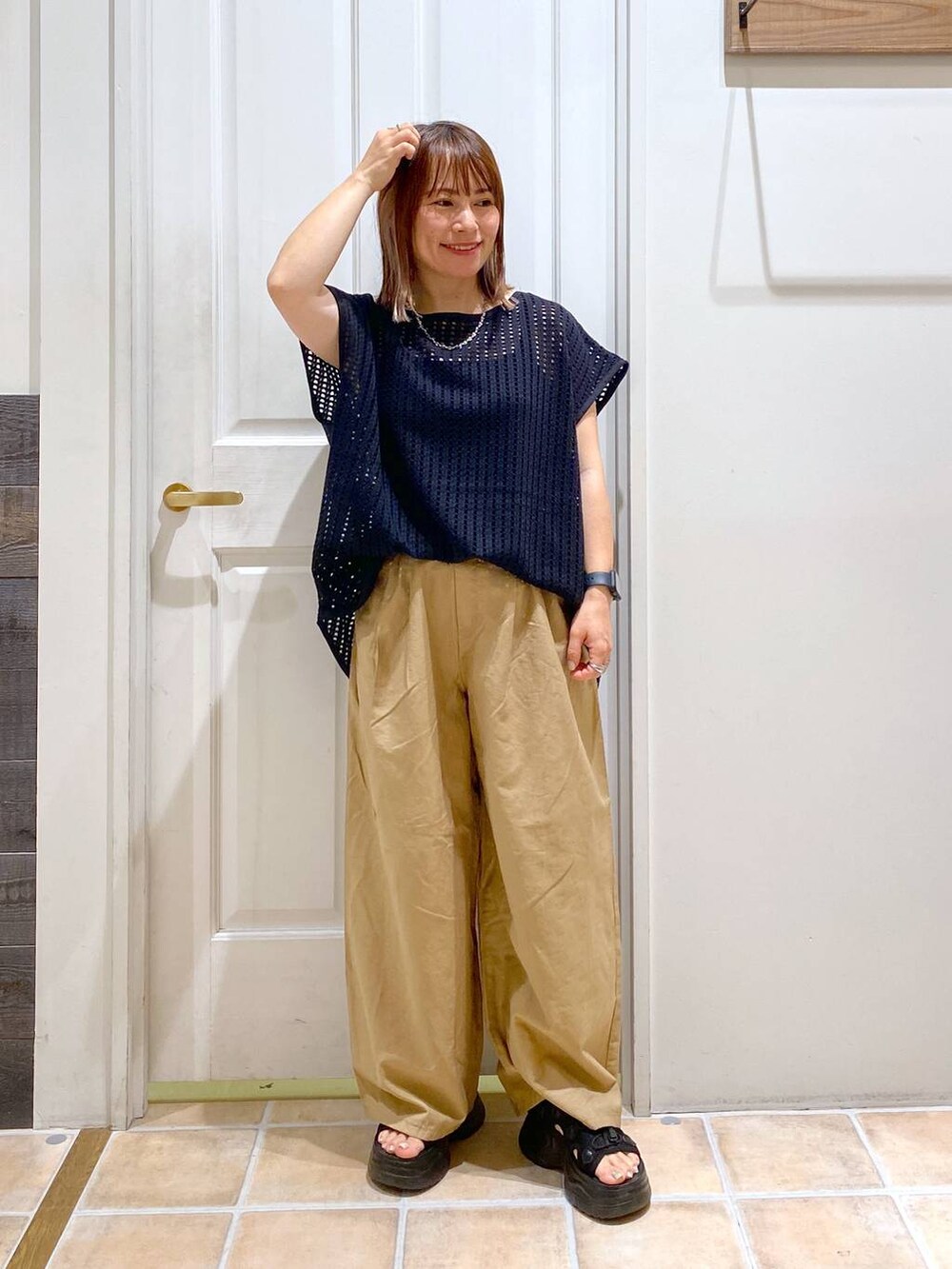 ブラック系のサンダル、ベージュ系のその他パンツ、ブラック系のTシャツ/カットソーを着用したレディースの夏コーディネートの2枚目の写真