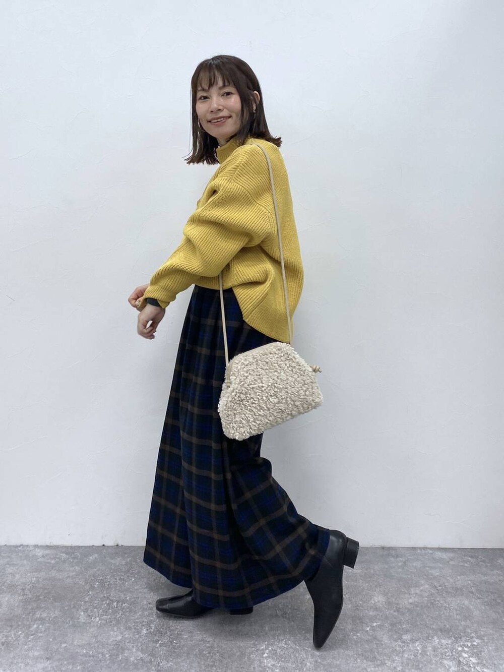 ブラック系のブーツ、イエロー系のニット/セーター、ベージュ系のトートバッグを着用したレディースの秋コーディネートの4枚目の写真
