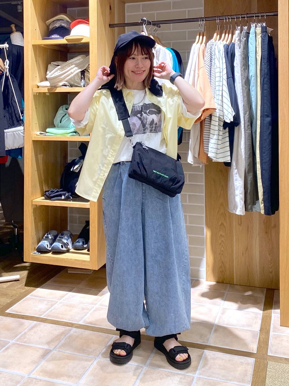 イエロー系のシャツ/ブラウス、ブラック系のサンダル、その他のTシャツ/カットソーを着用したレディースの春コーディネートの2枚目の写真